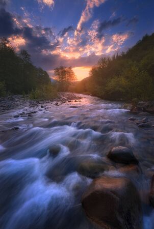 beautiful sunrise over fast flowing mountain riverの写真素材