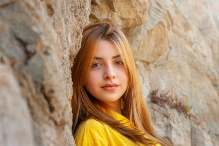 Beautiful teenage girl in yellow shirt in old city park