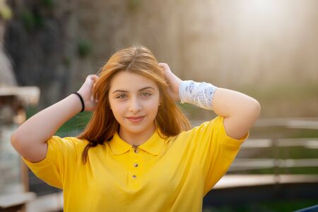 Beautiful teenage girl in yellow shirt in old city parkの写真素材