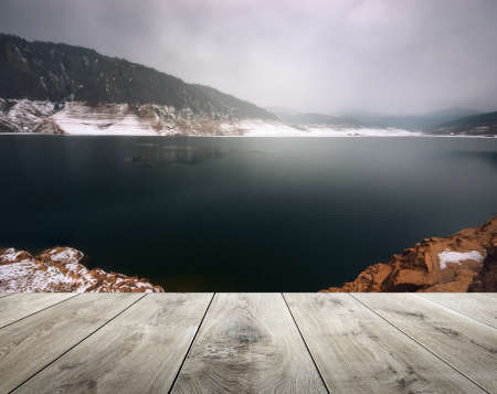 Winter beautiful background with misty lake and empty wooden table in nature outdoor. Natural...