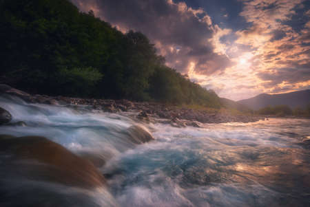 Beautiful sunny summer landscape. Sunset over fast flowing mountain river.
