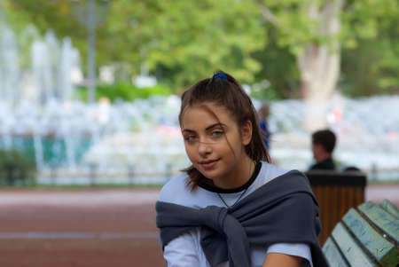 Cute teen girl posing in a city park at autumn evening.