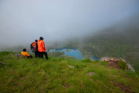 Georgia, Khevsureti - July 9, 2017: Three friends enjoy the beauty of a misty mountain lake.
