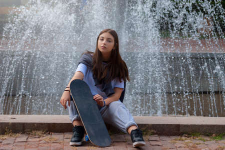 Cute teen girl posing in a city park at autumn evening.の写真素材
