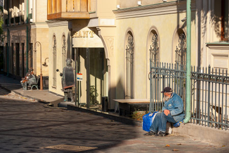 Georgia, Tbilisi - November 22, 2020: A tired old man is sitting on the street.のeditorial素材