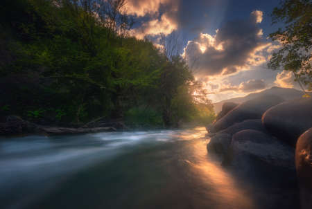 Magical sunset over fast flowing mountain river.の写真素材