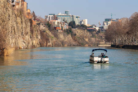 Georgia, Tbilisi - March 17, 2021: Tourists ride on a pleasure boat along the Mtkvari, Kura River.のeditorial素材