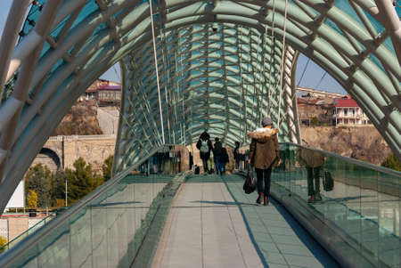 Georgia, Tbilisi - March 17, 2021: People walk on the Peace Bridge in Tbilisi.のeditorial素材