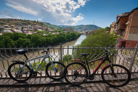 Georgia, Tbilisi - May 18, 2021: Bicycles in front of a beautiful view of the city.のeditorial素材