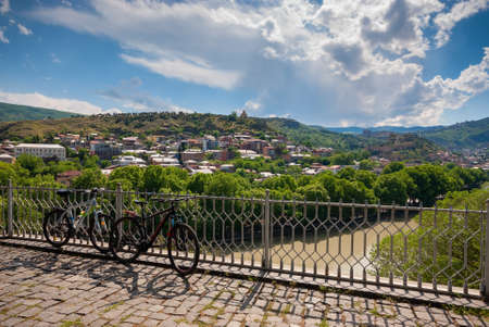 Georgia, Tbilisi - May 18, 2021: Bicycles in front of a beautiful view of the city.のeditorial素材