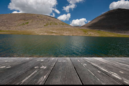 summer mountain landscape. Beautiful lake in mountains with empty wooden table.