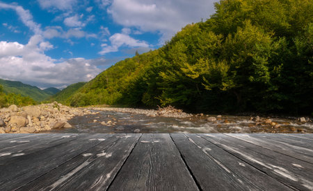 Fast mountain river flowing with empty wooden batten bridge. natural template landscape.の写真素材
