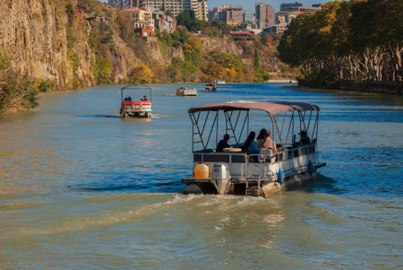 Georgia, Tbilisi - October 30, 2022: Tourists ride on a pleasure boat along the Mtkvari, Kura River.のeditorial素材