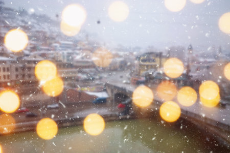Beautiful winter blurred background of Tbilisi city with falling snow and bokeh lights.の写真素材