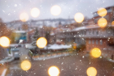 Beautiful winter blurred background of Tbilisi city with falling snow and bokeh lights.の写真素材