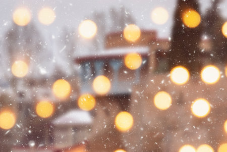 Beautiful winter blurred background of Tbilisi city with falling snow and bokeh lights.の写真素材
