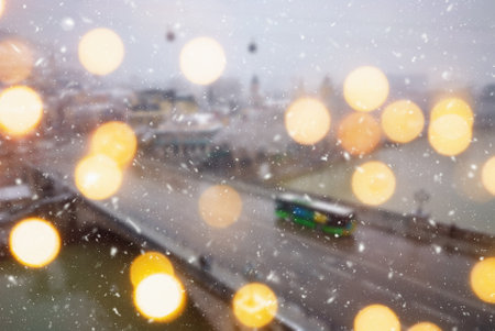 Beautiful winter blurred background of Tbilisi city with falling snow and bokeh lights.の写真素材