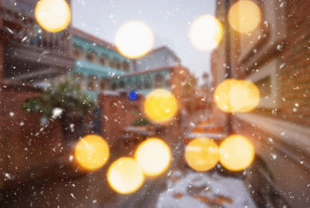 Beautiful winter blurred background of Tbilisi city with falling snow and bokeh lights.の写真素材