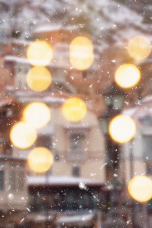 Beautiful winter blurred background of Tbilisi city with falling snow and bokeh lights.の写真素材