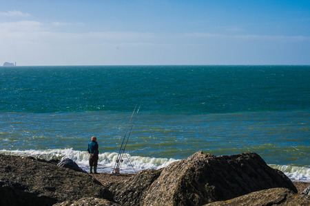 Sea angler fisherman attending to his rodsの写真素材