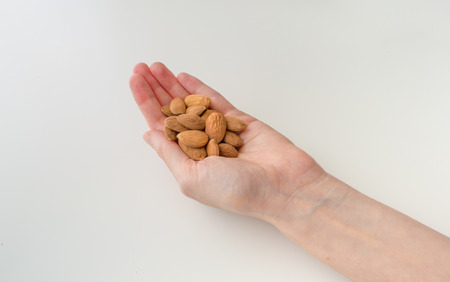 Woman's Hand Holding Almonds on a White Backgroundの写真素材