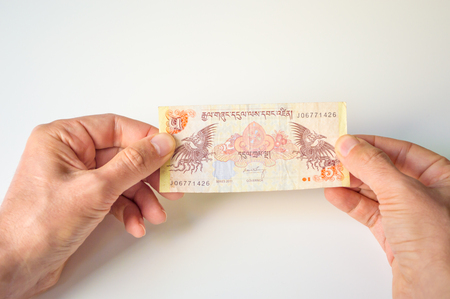 Man holding five Bhutanese Ngultrum banknote in his handsの写真素材