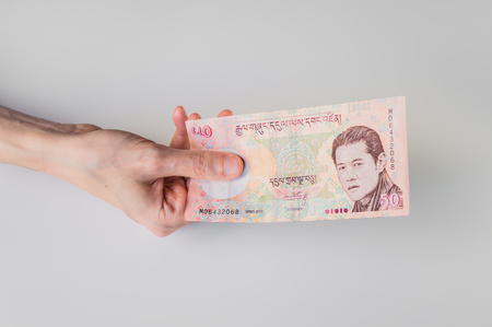 Woman holding fifty Bhutanese Ngultrum banknote in her handの写真素材