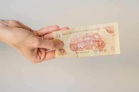 Woman holding five Bhutanese Ngultrum banknote in her handの写真素材