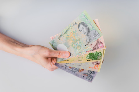 Woman holding a bunch of Bhutanese Ngultrum banknotes in her hand