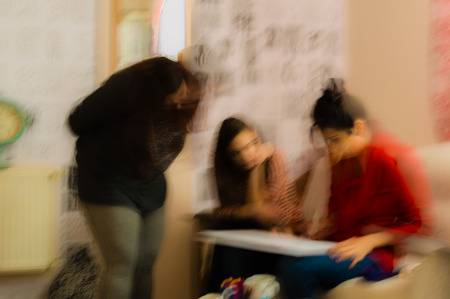 Blurred abstract view of young students watching the artist drawings on paper in a room