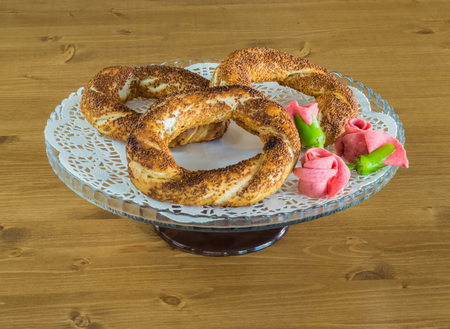 Traditional Turkish Pastry (Simit) with salami served on glass plate on a wooden table