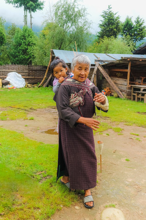 Bumthang, Bhutan - September 13, 2016: Old Bhutanese woman with a child in a village in Bumthang valley, Bhutan.のeditorial素材