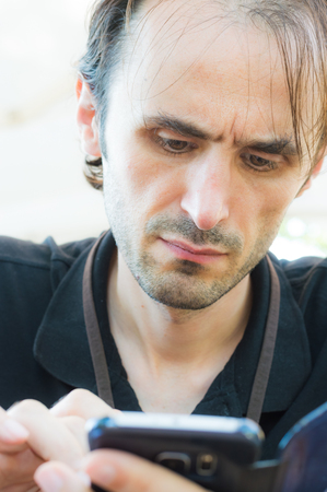 Portrait of a young, handsome, Caucasian man with stubbly beard using mobile smart phoneの写真素材