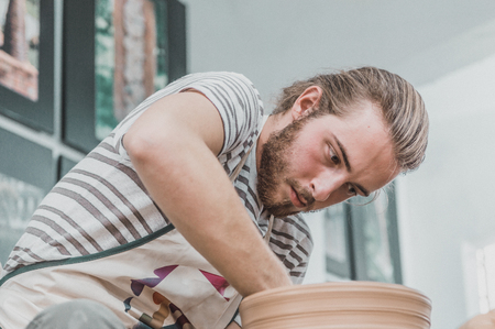 Young pottery artist working on his clay pot in an atelierの写真素材