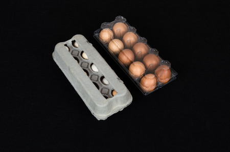 Twenty chicken eggs in carton and plastic boxes, isolated on black felt background.