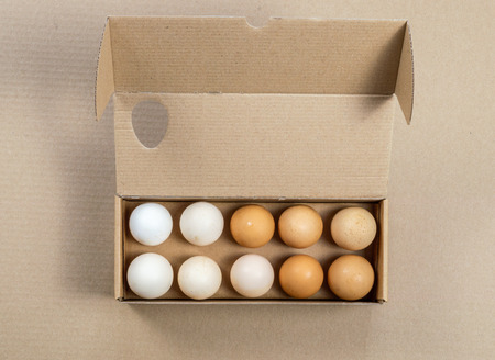 Top view of carton egg container with fifteen eggs on a brown background.