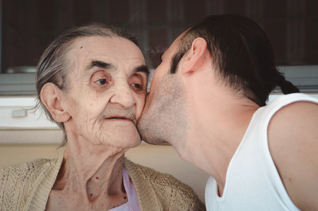 Young man kissing his grandmother's cheek, showing his love, respect and gratitude.の写真素材