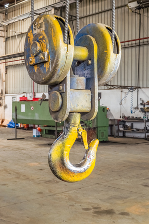 Closeup of a industrial yellow lifting crane hook in a factory.
