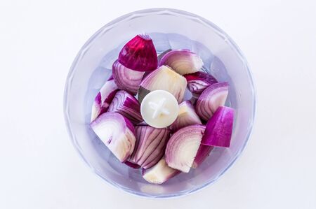Top view of purple onions in a blender on a white background. Food preparation concept.