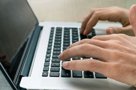 Male freelancer using laptop while sitting on a comfortable couch at home. Freelancing concept.