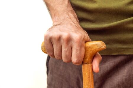 Close up of male hand with walking stick on white backround. Disability concept.