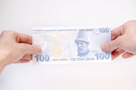 Female hand holding a 100 Turkish Lira (TRY) banknote isolated on white background.の写真素材