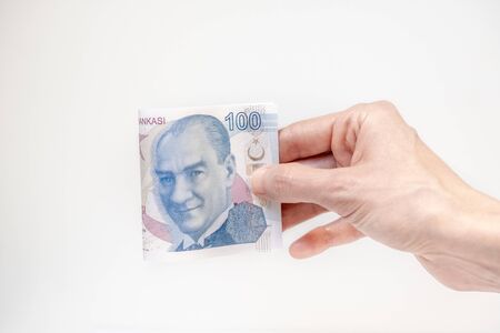 Female hand holding a 100 Turkish Lira (TRY) banknote isolated on white background.の写真素材