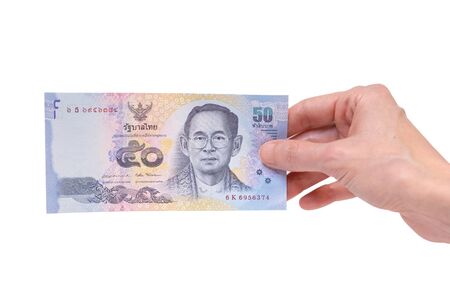 Female hand holding a 50 Thai Baht banknote isolated on a white background. Denomination of 50 Bahts.の写真素材