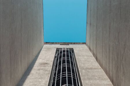 Low angle view of a spiral external fire escape staircase of a building with blue sky.
