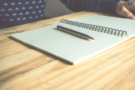 A book and pen on the table brown wood.の写真素材