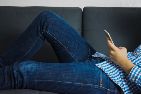 People are lying playing phone on the sofa.の写真素材