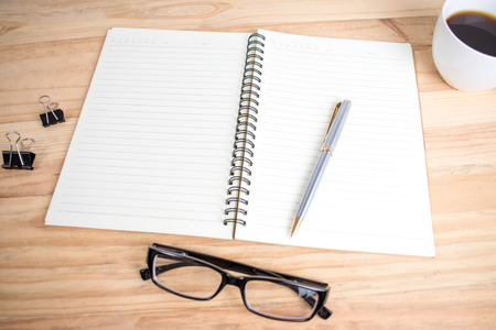 On the brown wood table there is a pen and notebook ready for work.の写真素材