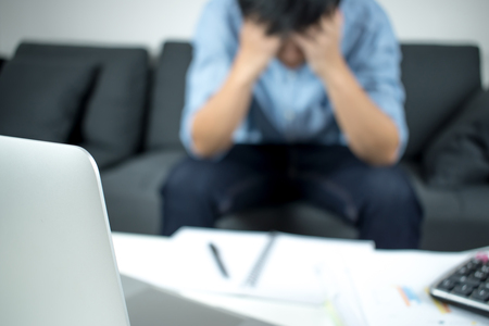 Blurring of people sitting on the sofa, who are feeling stressed with his work.の写真素材