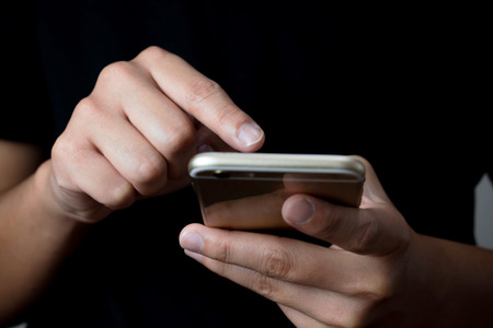 Close-up photo of a man using technology on a phone in the room. Concept Technology Contact.